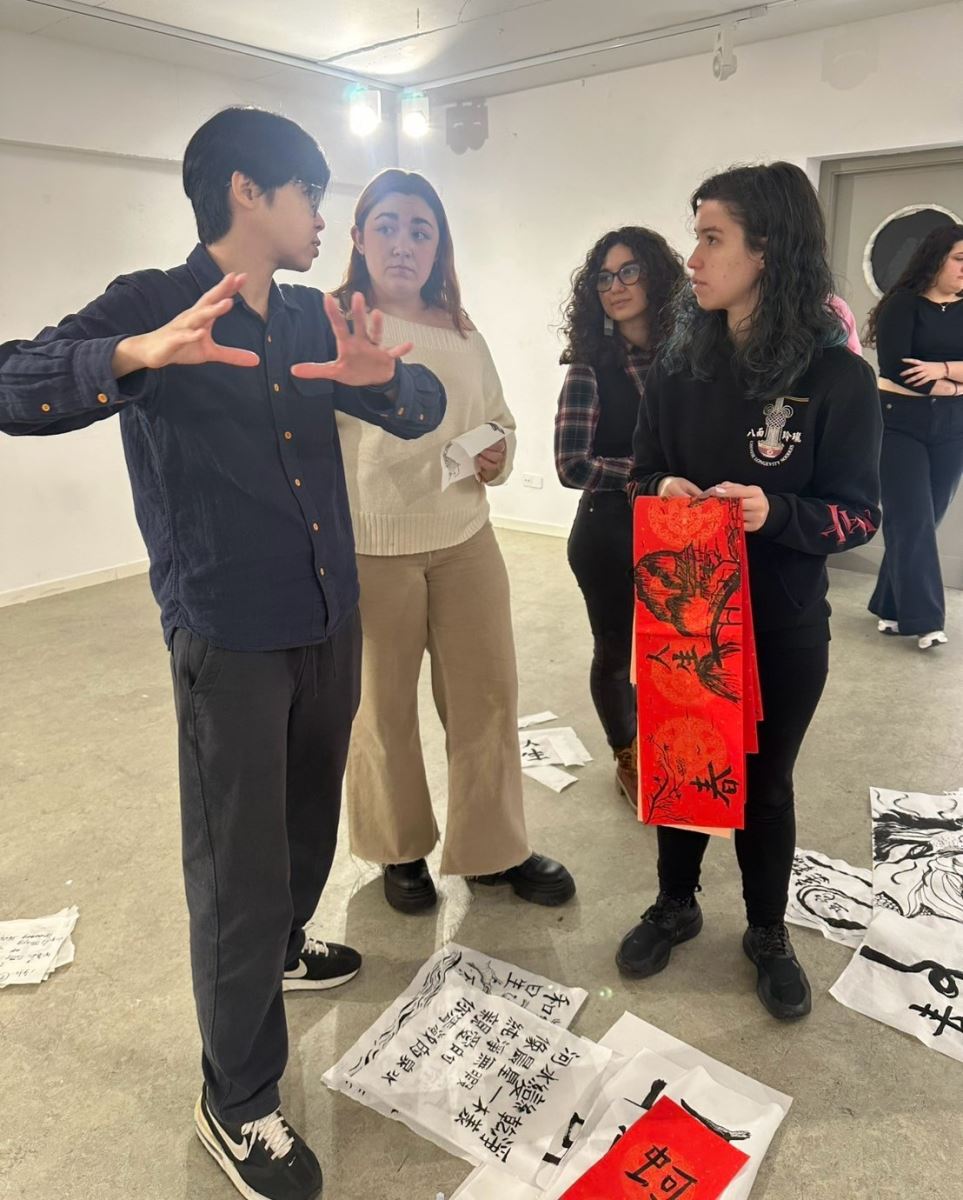 華梵大學教授藝術家楊侖（左一）指導西班牙學生為書法創作布展。
