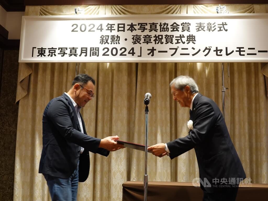 華梵大學攝影與VR設計學系沈昭良教授從日本寫真協會代表理事會長青木良和手中接過獎狀與獎座。